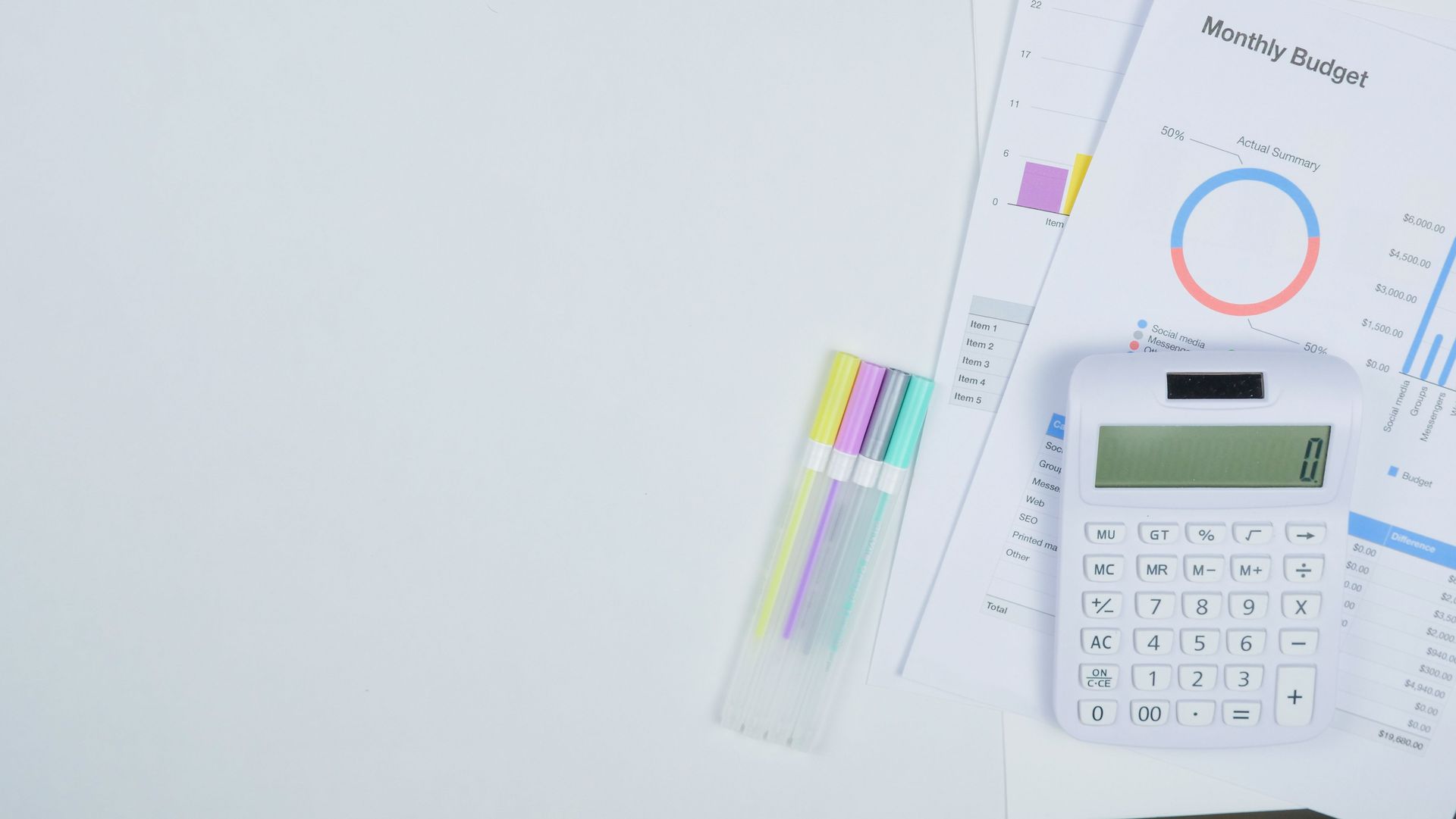 Minimalist office desk with a calculator, budget planning documents, and colorful pens.